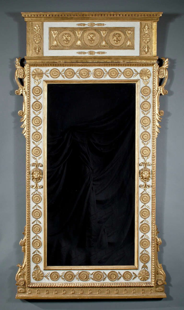 Rectangular Neoclassical mirror, the wide gray painted frame comprised of regularly spaced circular gilt rosettes within a narrow chanelled, gilt border, surmounted by a rectangular panel containing a frieze of three circular lion's heads in low