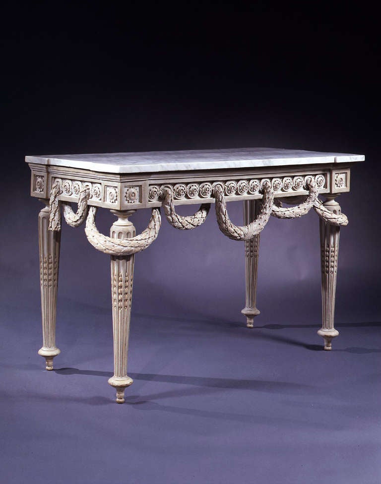 Rectangular shaped white marble top above a freeze with guilloche band centered with flowerheads having a berried laurel threaded throughout the front and sides, raised on paterae headed turned and tapering fluted legs part-filled with
