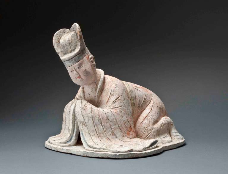 Tang Dynasty, 8th century

The recumbent figure with red, black, yellow, and green pigments, modeled in a kowtowing position, kneeling with the legs splayed and resting on the elbows, the head raised and slightly turned to the left, the plump face