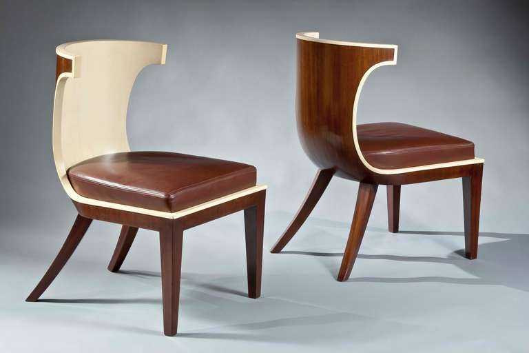 The pair fashioned with barrel backs sculpted out of veneered mahogany and white lacquered interior which continue onto the square seat rail. The whole rests upon saber form rear legs and a square tapering anterior legs.

Born 1881 in Lausanne,