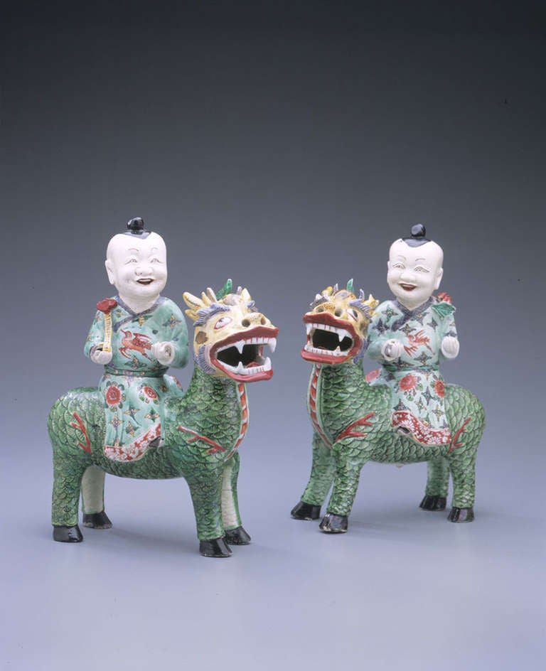 Modeled in mirror image, each grouping depicting a smiling boy seated on the back of a kylin, turning towards the viewer with the hands raised, one boy holding a lotus branch and the other with a ruyi scepter, the beast standing foursquare, molded