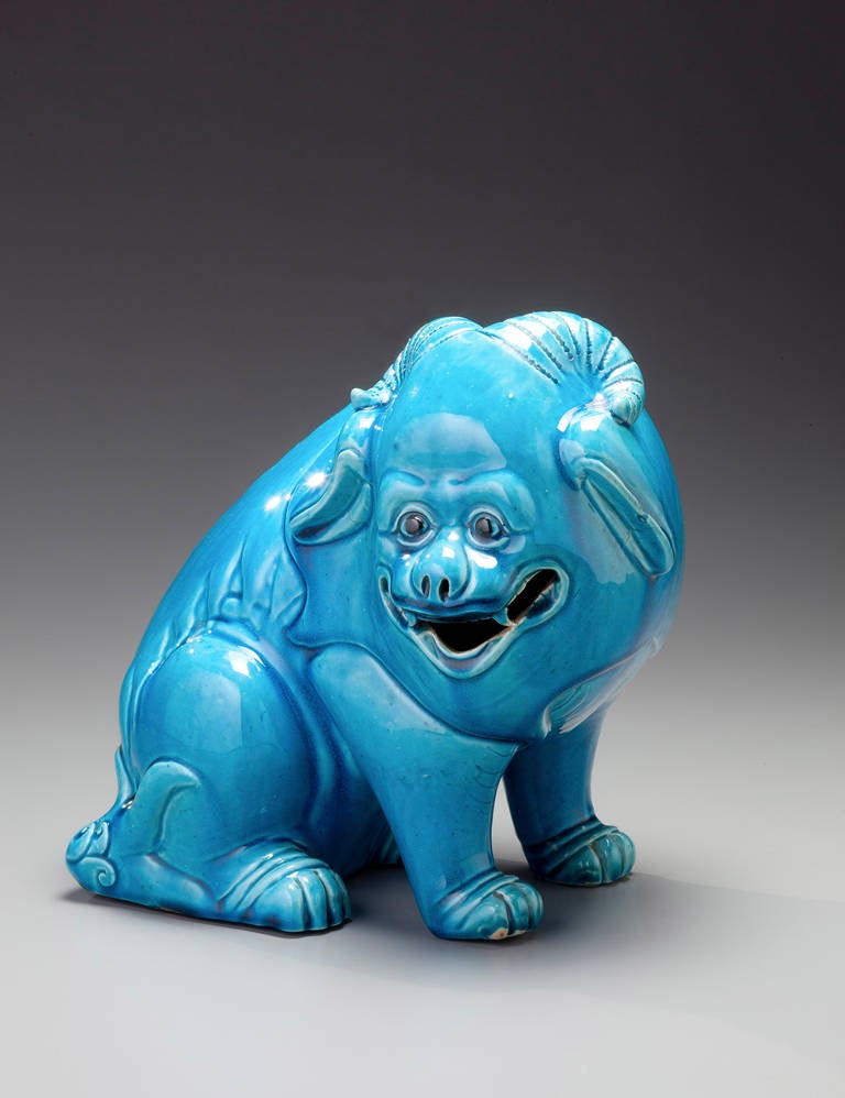 A seated dog with two horns with turquoise surface glaze.