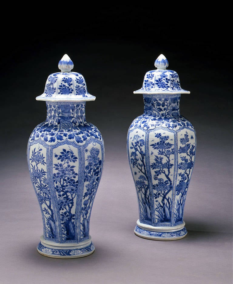 Each vase of octagonal section supported on a tall foot topped by a circular platform surmounted by a high-domed cover and bud form knop, painted in underglaze blue. The body decorated with eight pointed foliate panels outlined by a square scroll,