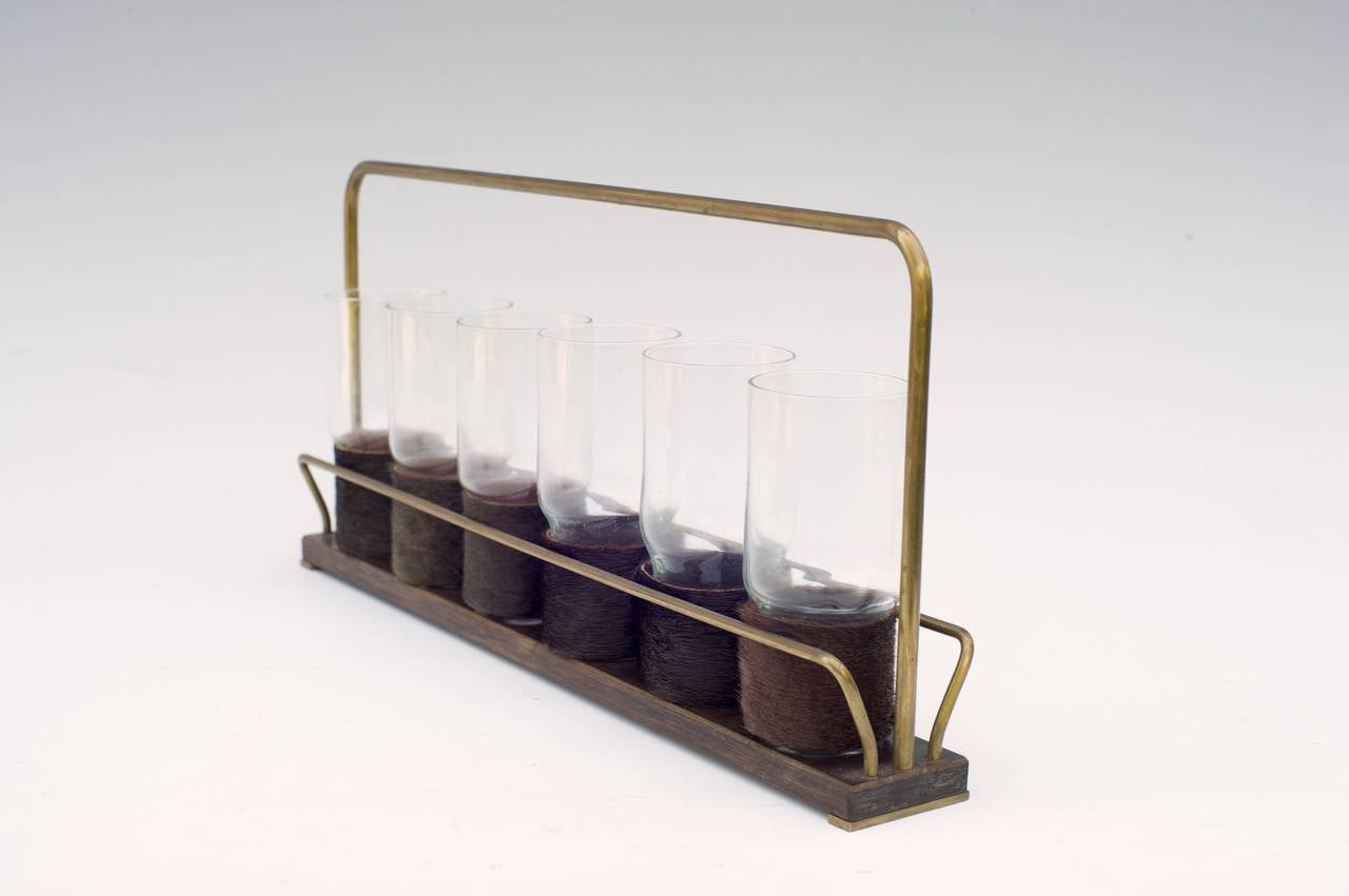 Set of six drinking glasses in a carrying rack
by Carl Auböck

Glass, fur, brass, wood

Glasses: Ø 4.7 cm / 1.85 inches, H 10.5 cm / 4.13 inches

Good condition with traces of usage and aging.