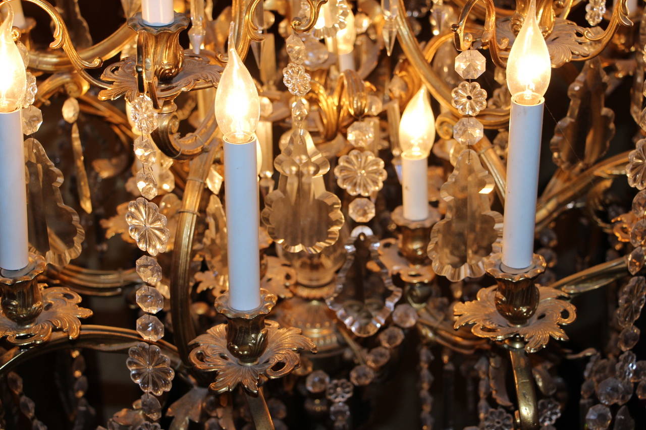 This spectacular French chandelier features three tiers of lights with a total of twenty four lights. It is all solid bronze and cut crystal in the Louis XV style.
 