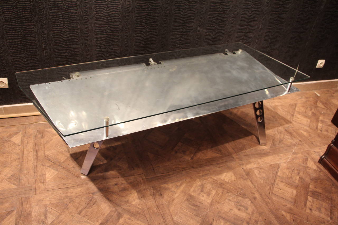 This magnificent mirror polished aluminum coffee table was born from a flap of Harrier Jump Jet.It has got a glass top.
It has got 3 sturdy solid aluminum legs and is perfectly well balanced.
It is a very decorative and unusual piece.