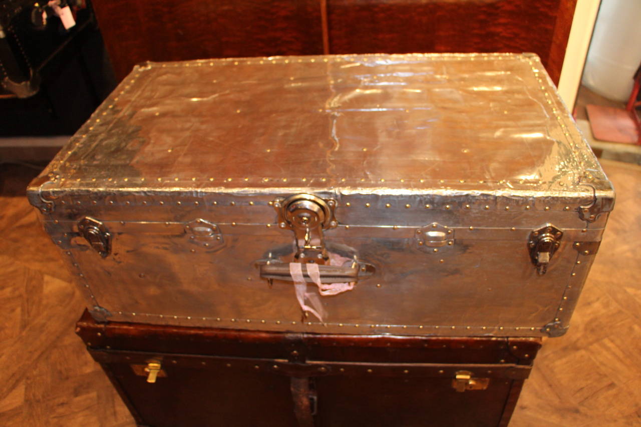This polished aluminium cabin trunk is very unusual and has got brass studs.
It is magnificent and mirror polished.
Its interior has kept its original light grey fabric. 
It would be perfect as a coffee table.