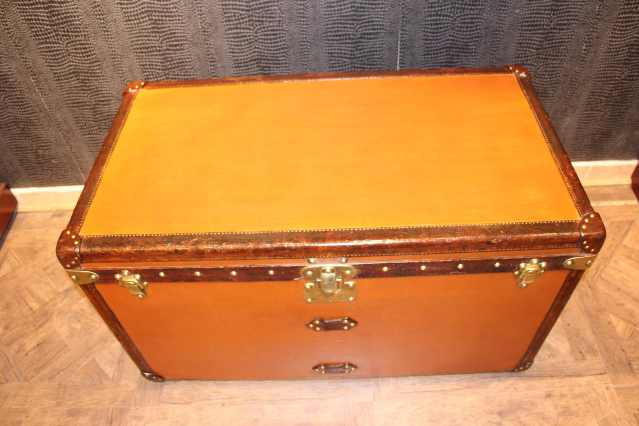 This unusual orange Vuittonite canvas courrier trunk has got all leather trim and handles,brass corners and locks;It has a beautiful warm orange patina.
The interior is perfectly original with beige linen and features one wevved basket,one half