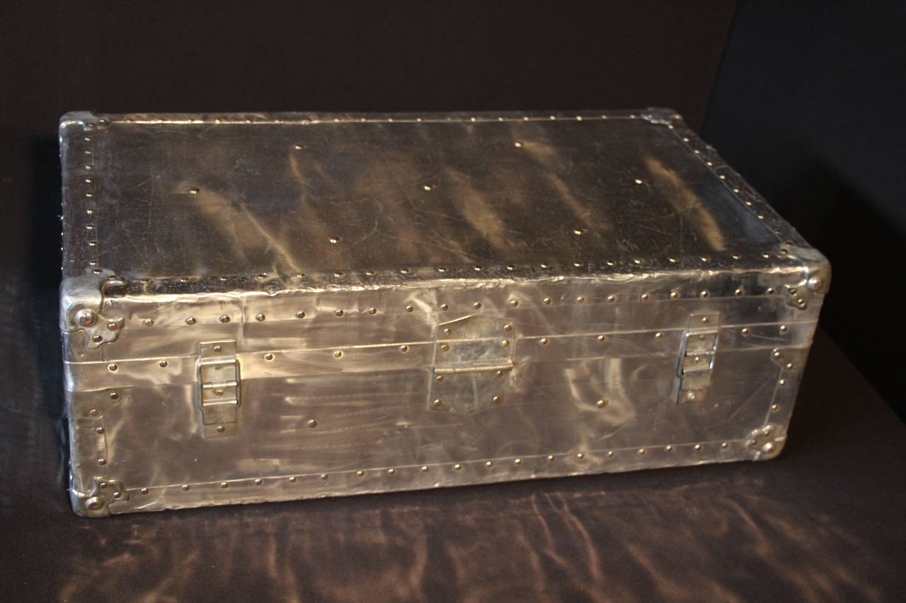 This polished aluminium cabin trunk is very unusual and has got brass studs.
It is magnificent and mirror polished.
Its interior has kept its original  fabric.
It would be perfect as a coffee table.