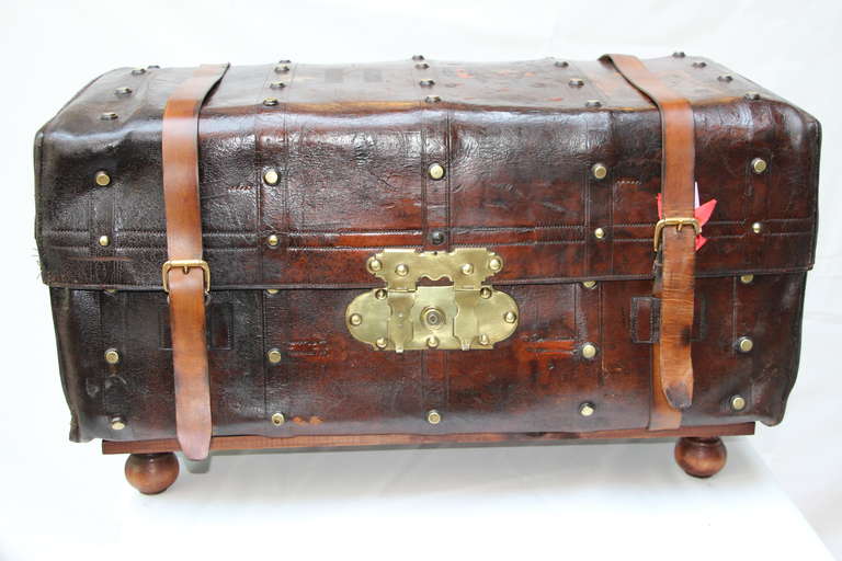 This English leather case has got a very warm patina and a nice job of brass studs on four rows.The double brass lock is very unusual.
A wood stand has been custom made in order to allow this trunk to be used as a coffee table.It has the perfect