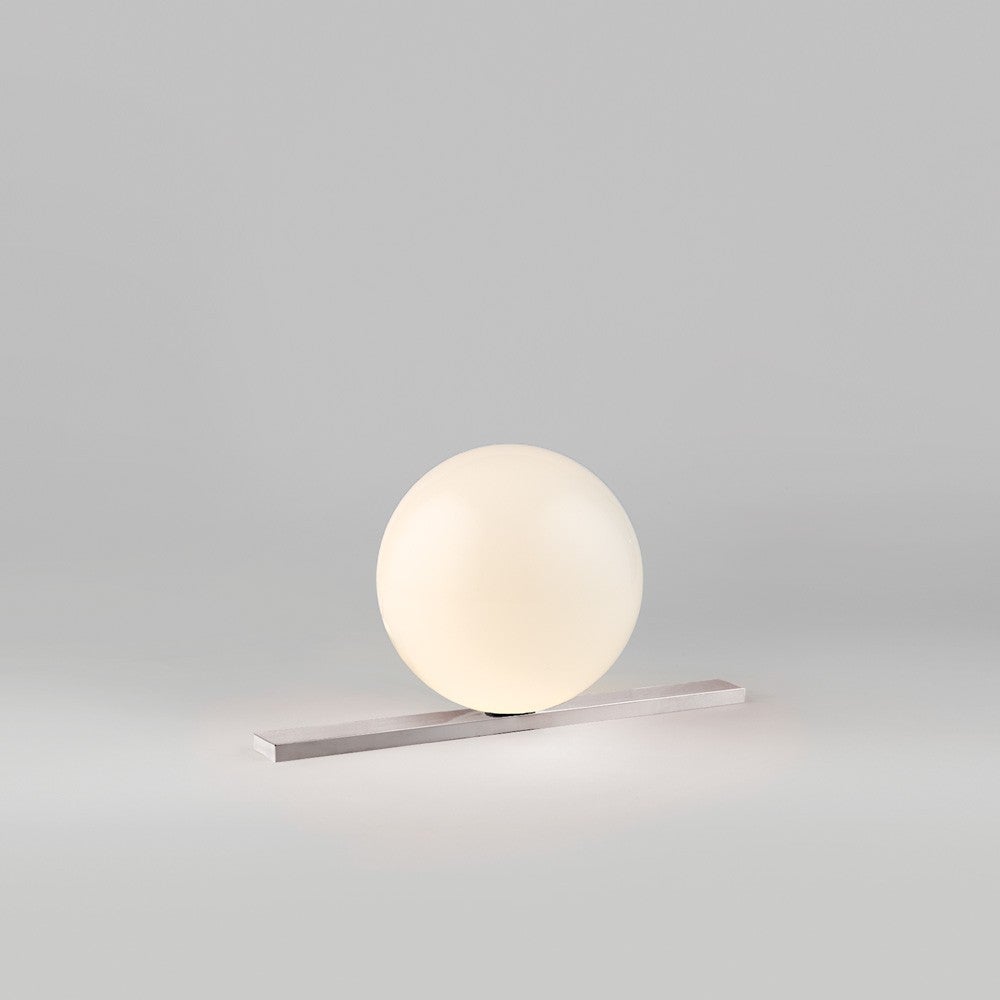 The Get Set light, a finely crafted table fixture from Michael Anastassiades, is made with mouth-blown opaline glass, which is formed into a sphere, and placed atop a polished brass or nickel base. This fixture comes with an inline switch, connected
