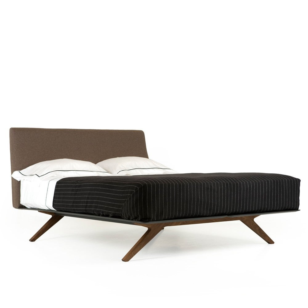 A luxurious upholstered bed with elegant simplicity and visual lightness achieved through the clever use of superb materials. Solid American black walnut or American white oak legs in a unique shape elegantly raise the slender body of the bed.