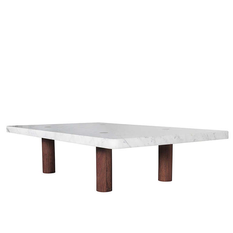 Expanding on the “Column” table series, this large column coffee table by Fort Standard features a two inch thick slab of white Carrera marble which sits on four inch diameter Walnut legs. The legs feature a shoulder which supports the table top and