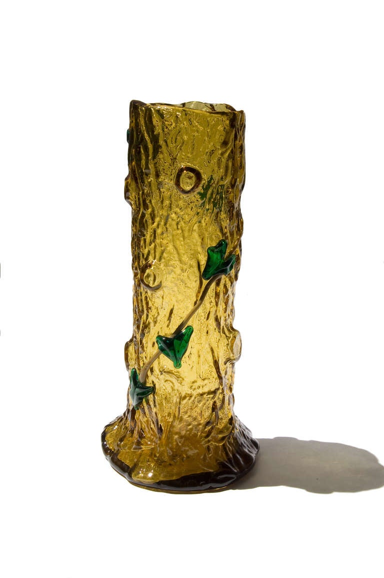 Amber color Crystal Vase molded by blown with a tree stump shape. 
Patched and heat welded putty color branch and green foliage.

Carved and enameled signature: 'A. Jean' (brown color) under the base.

Height: 30 cm / 10.8in.
Base diameter: