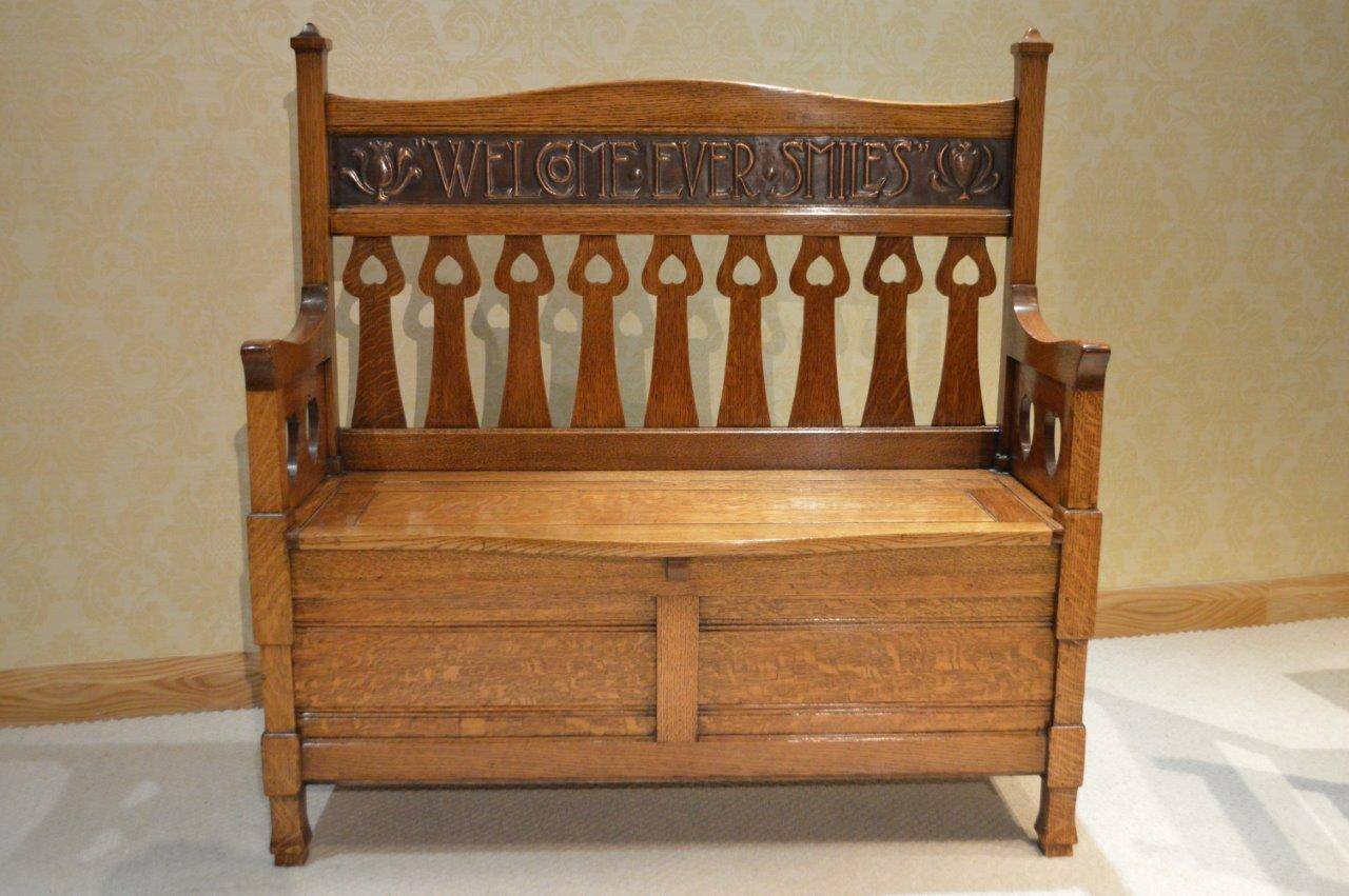 A rare oak Arts & Crafts Period bench by Shapland & Petter Of Barnstaple. Having a shaped back with typical Shapland & Petter pierced heart tulip supports and with a hand beaton copper panel 