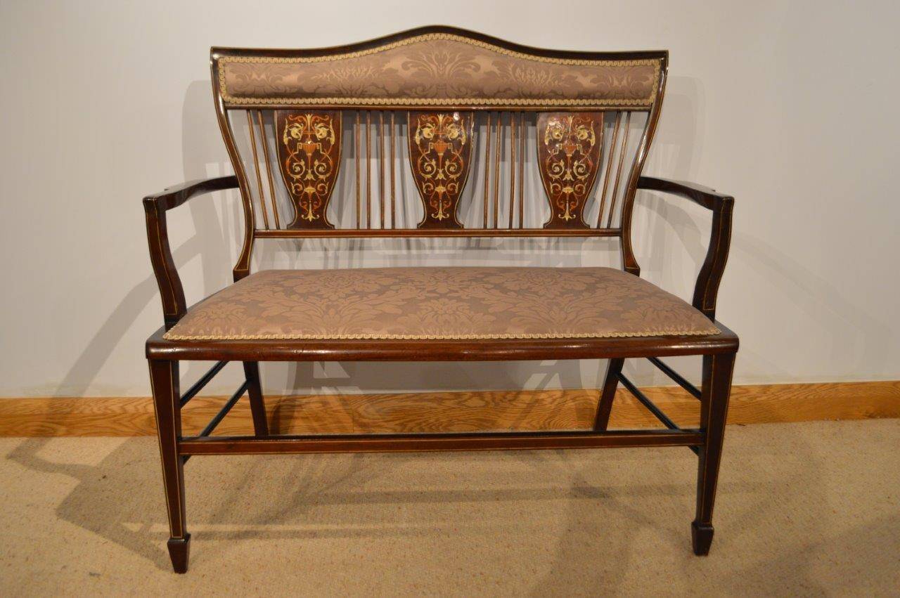 A mahogany & marquetry inlaid Edwardian Period antique settee/sofa. The back having a shaped padded support above three vase shaped splats with fine marquetry and pen-work panels and vertical support spindles. Having open swept arms above the