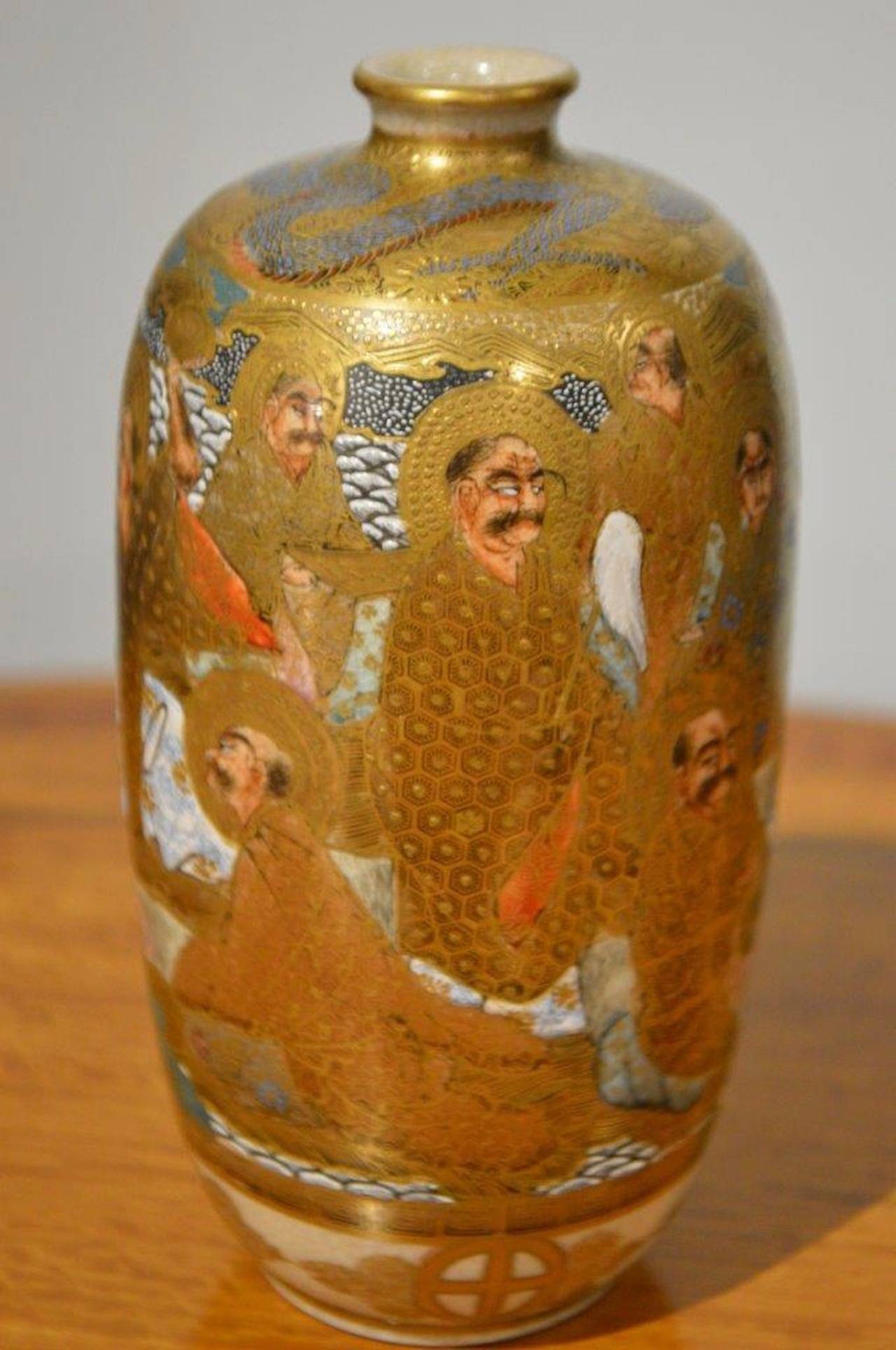 A Meiji Period Japanese Satsuma vase. The vase of ovoid form and with gilt ground, raised enamel and hand painted detail. The base in white ground with Japanese 