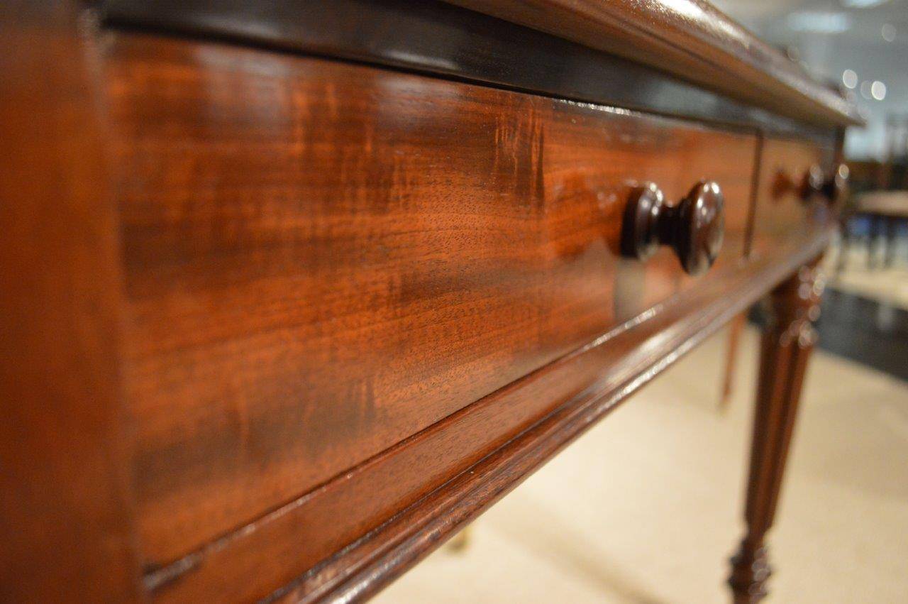 A mahogany Regency Period mahogany two drawer antique side table probably by Gillows Of Lancaster. With a raised shaped mahogany galleried back and a well figured Cuban mahogany top above two mahogany lined frieze drawers, with turned mahogany