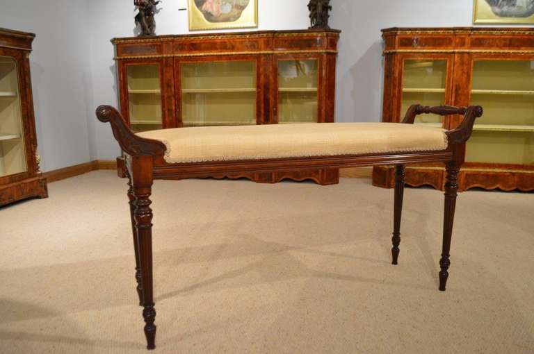 A mahogany Late Victorian Period antique window seat/duet stool. Each side with a beautifully turned mahogany rail, supported on carved supports. The rectangular seat newly upholstered in a beige silk Zoffany fabric. The whole raised on elegant