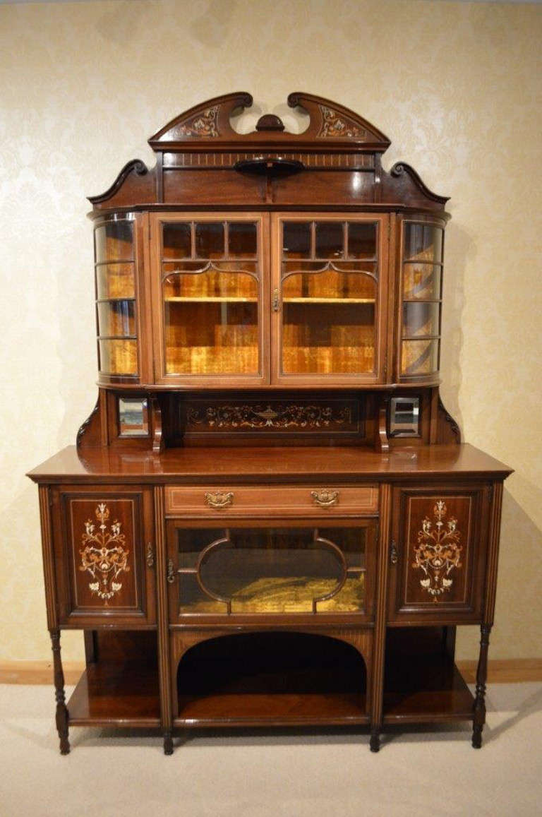 A mahogany inlaid Late Victorian Period antique chiffonier by Maple & Co. The upper section with a broken swan neck pediment, floral marquetry and ivory inlaid detail above a bevelled glass display section, lined in the original gold velvet. The