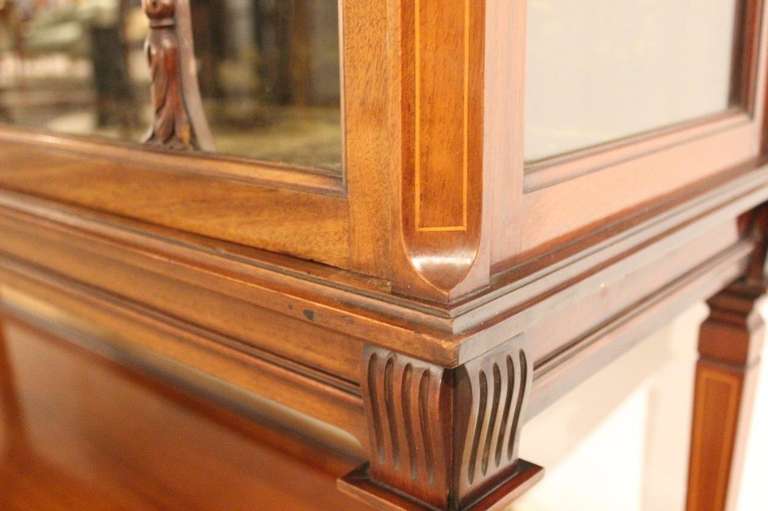 A mahogany and satinwood Edwardian Period antique china cabinet. Having a projecting mahogany cornice with dentil moulded detail above a satinwood and marquetry inlaid frieze, centred by a wedgwood plaque. Having twin glazed doors which open to