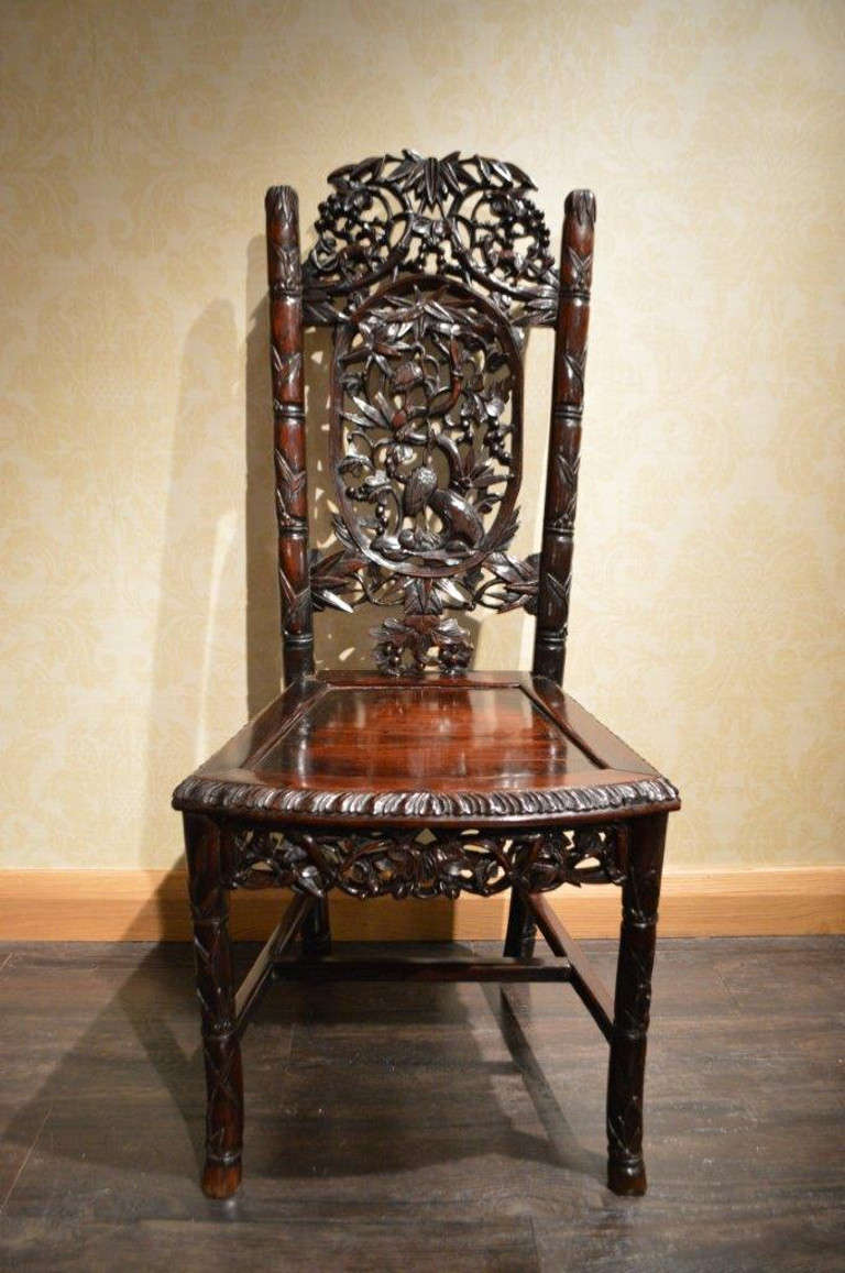 An unusual Hardwood Chinese antique chair. Having an elaborately carved pierced back depicting cranes and other animals amongst foliage with faux carved bamboo supports above the panelled seat with a gadrooned carved border. Supported on faux bamboo