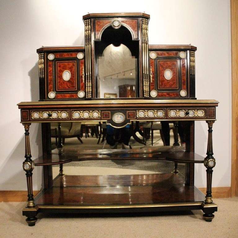 An amboyna, ebony and ormolu mounted Victorian Period bonheur de jour. The upper section having a brass balustrade gallery, a central open display section with mirrored back and sides. The canted corners having applied ormolu mounts and flanked by