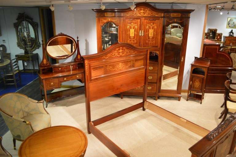 A magnificent rare mahogany inlaid Late Victorian Period antique bedroom suite purchased from a Scottish Country house consisting of a mahogany inlaid Princess wardrobe, a dressing table, a double bed and a bedside cabinet. The wardrobe having a