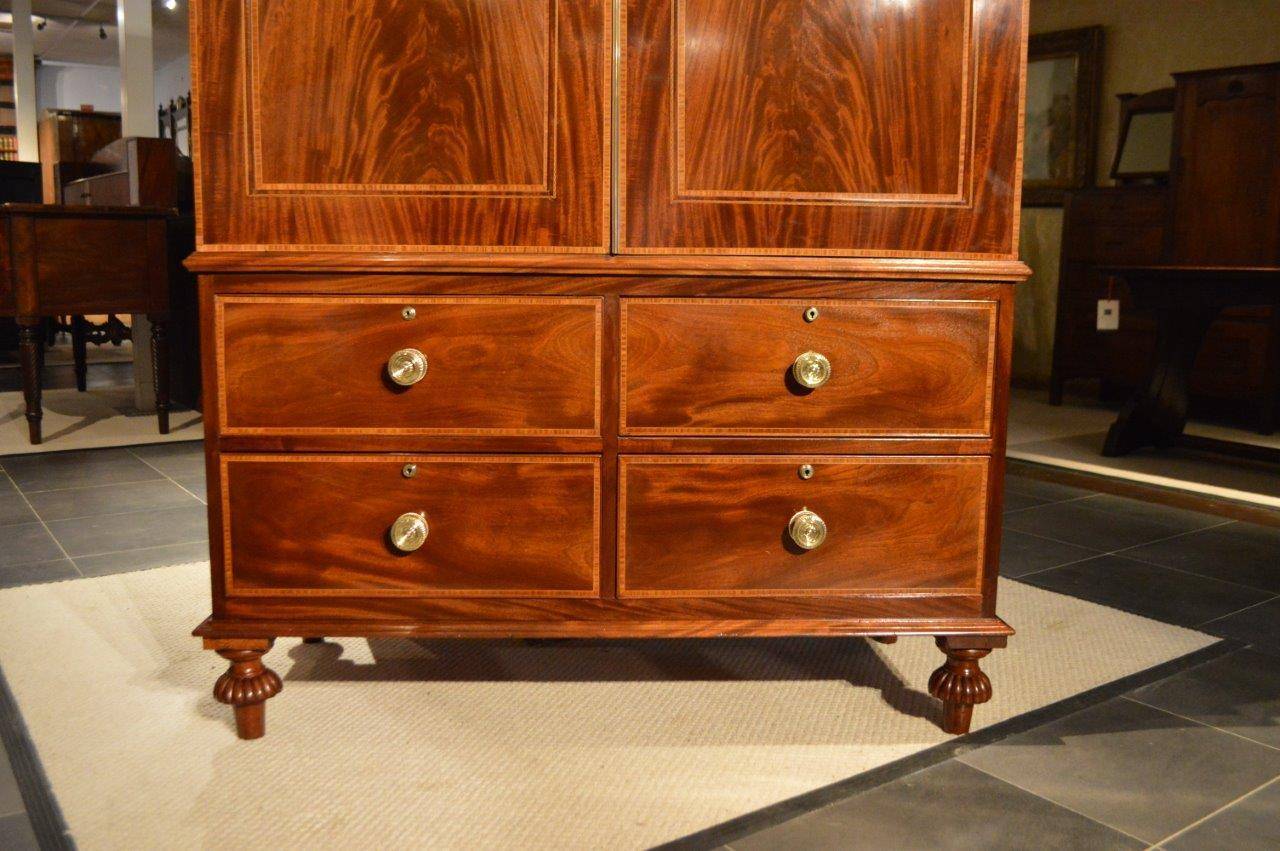 A fine quality mahogany inlaid Edwardian Period antique press/wardrobe. The upper section with a traditional stepped moulded cornice with satinwood banding and chequer band marquetry inlaid detail, above twin arched panelled doors constructed in the