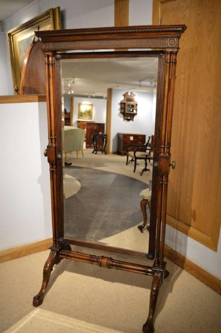 A mahogany Chippendale Revival antique cheval dressing mirror. Having a moulded cornice with Greek Key moulded detail above an arcaded frieze with carved paterae, raised on four cluster column supports with cast brass adjusters. The central