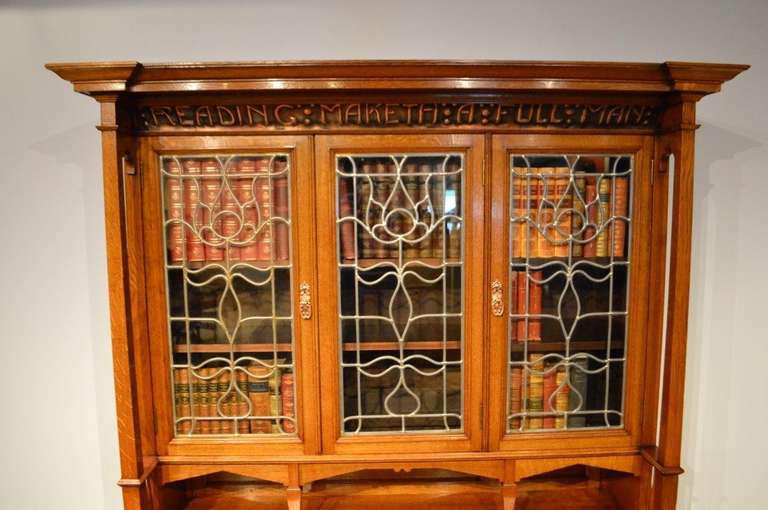 A rare oak Arts & Crafts period bookcase by Shapland & Petter. The upper section with a projecting inverted breakfront cornice above the concave frieze 