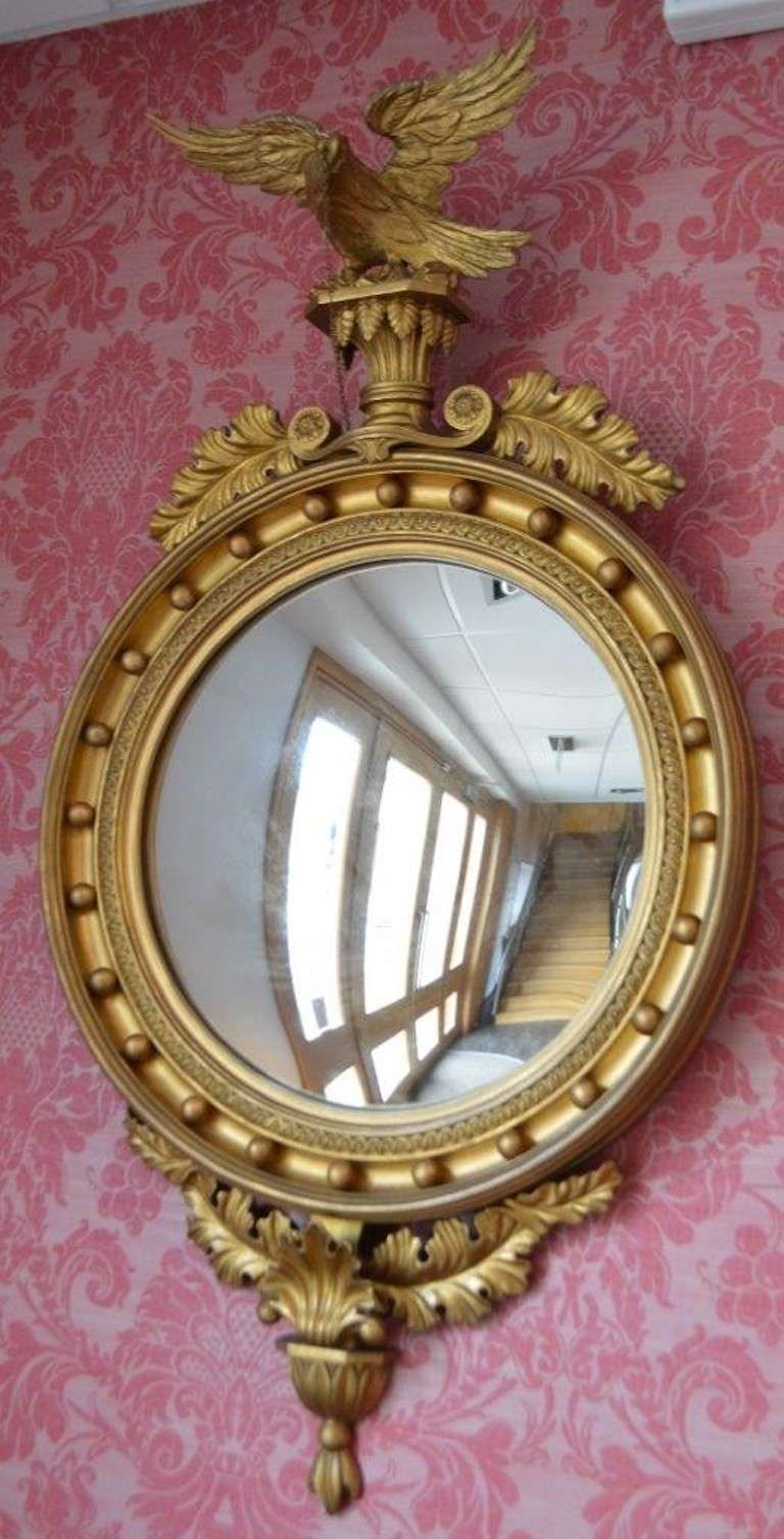 A gilt wood & Gesso Regency Period antique convex mirror. Having an elaborately carved giltwood crest surmounted by a carved giltwood eagle above the traditional circular convex mirror. With applied gesso ball work detail and a carved shell crest.