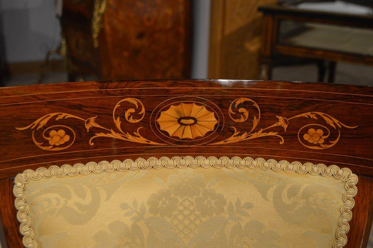 A rosewood inlaid Late Victorian Period antique desk/armchair. The shaped solid rosewood back with marquetry inlaid detail and a padded back rest. Having open swept arms above a generous sprung seat newly re-upholstered in a gold silk damask.