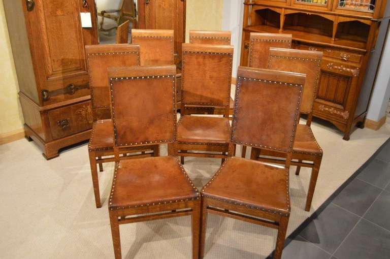A rare set of eight Arthur Simpson oak antique dining chairs. Each chair with a slightly raking back and a gently curving top rail. The backs having the Simpson trade mark wonderful leather panels with brass studded detail, which is repeated on the