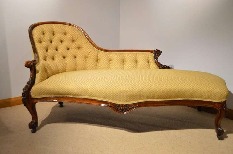 A beautiful walnut Victorian period antique chaise longue. The deep buttoned shaped back with a walnut carved show frame and floral carved detail. The open end sprung seat re-upholstered in a Zoffany silk weave above the carved serpentine seat rail.