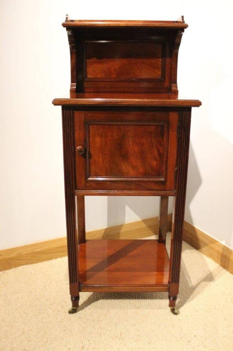 A mahogany Victorian period antique bedside cabinet by Holland & Sons. The raised galleried back with a protruding shelf above a solid mahogany rectangular top and with a single paneled door, stamped by the maker Holland & Sons. Supported on square