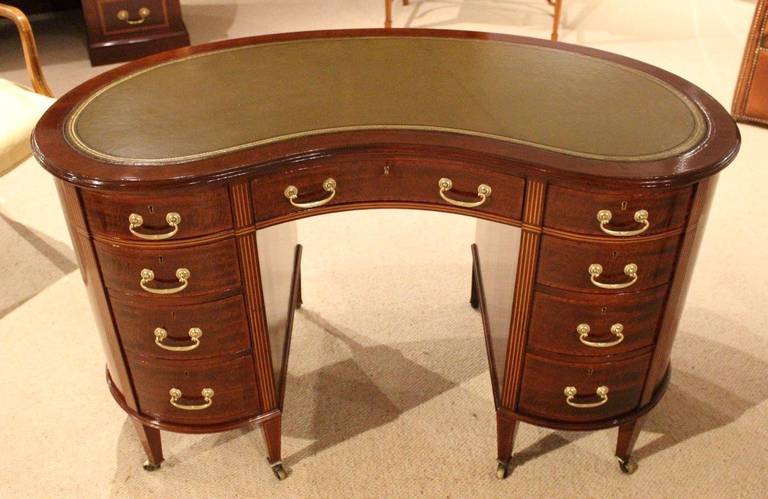 A beautiful mahogany inlaid late Victorian period kidney shaped desk. Having a solid fiddleback mahogany kidney shaped top with an inset olive green gilt and blind tooled leather with boxwood and ebony line inlaid detail. The pedestals having four