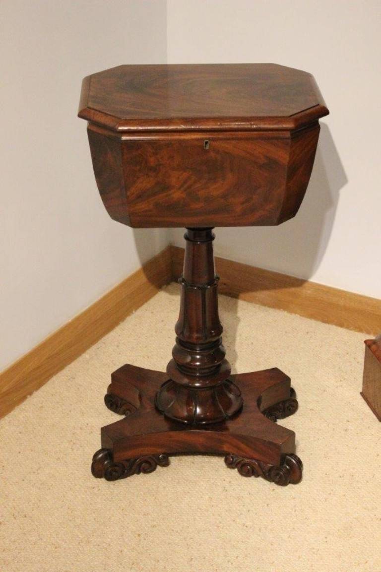 A mahogany William IV Period antique teapoy. The teapoy having a flame veneered mahogany octagonal top, which opens to reveal two original mahogany hinged tea canisters and vacant areas where originally two cut glass mixing bowls would have been.