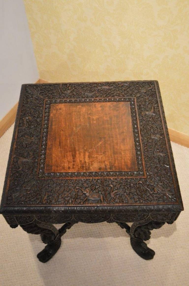 A 19th Century carved burmese antique side table. The square top made from padouk and having a richly carved border depicting various animals including elephants, monkeys, peacocks and with carved Hindu figures to the corners. Having a shaped