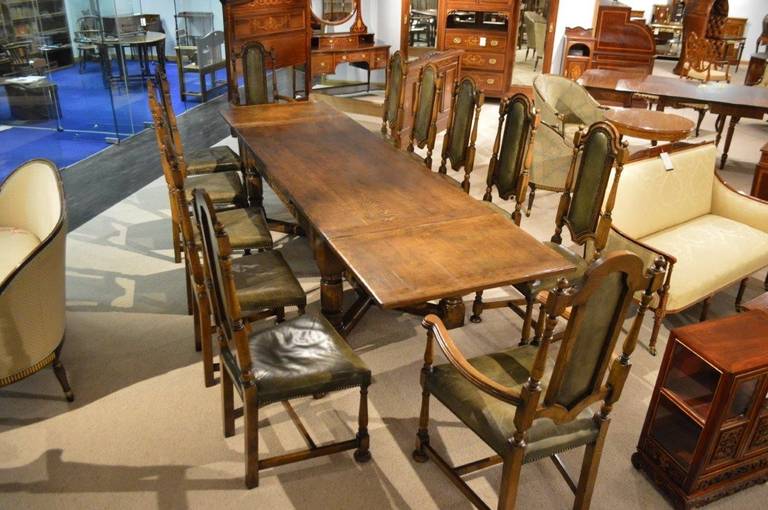 A Jacobean style oak refectory table and set of 12 oak dining chairs. The solid oak draw leaf table having a rectangular oak top with traditional cleated ends and twin cleated draw leaves which pull out from underneath the top and extend the table