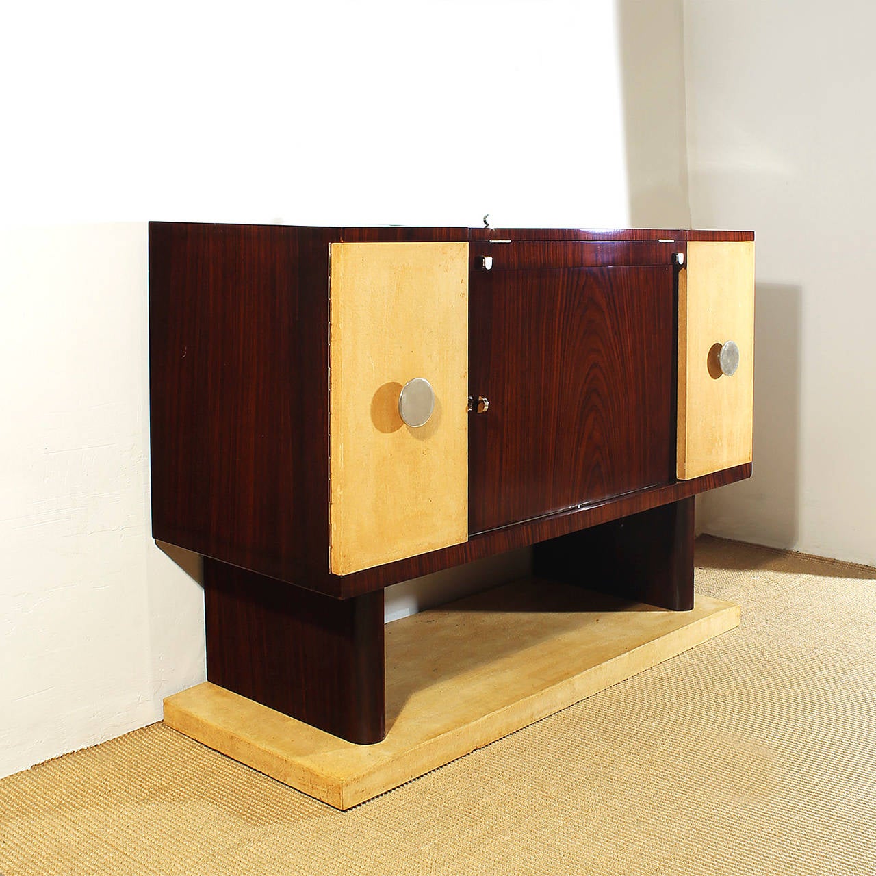 Small Art Deco system dry bar, rosewood veneer, french polish, 2 side doors covered with original parchment, one for bottles and the other one with 3 drawers, central pivotal door with places for bottles and glasses. Small flap plate on top for