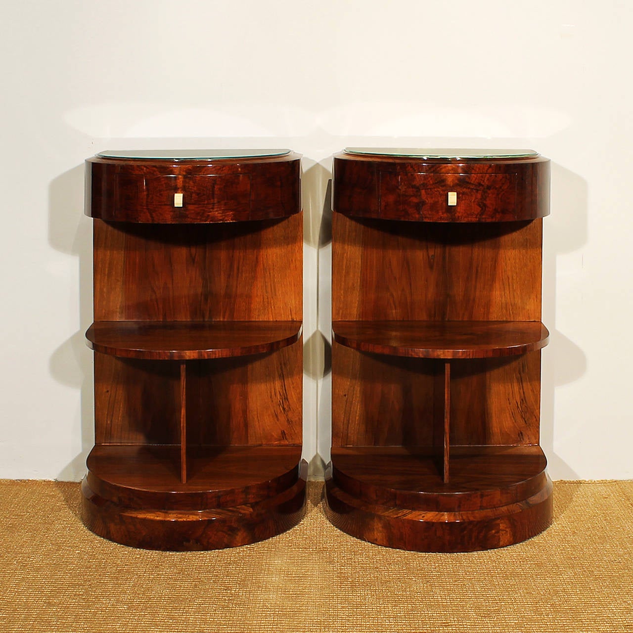 Pair of Art Deco semi-circular nightstands, walnut veneer, French polish, one drawer, two shelves, one with separation, bakelite handles, parchment and glass on top.
France, circa 1930.