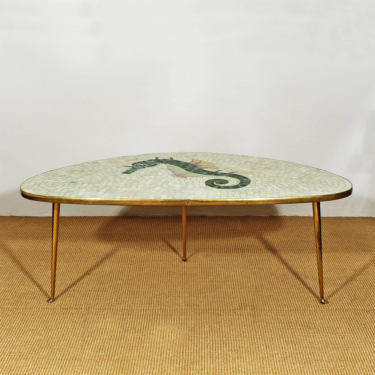 Nice tripod coffee table, ceramic mosaic on top with sea horse pattern, bright colours, brass feet and frame.
Italy c. 1950