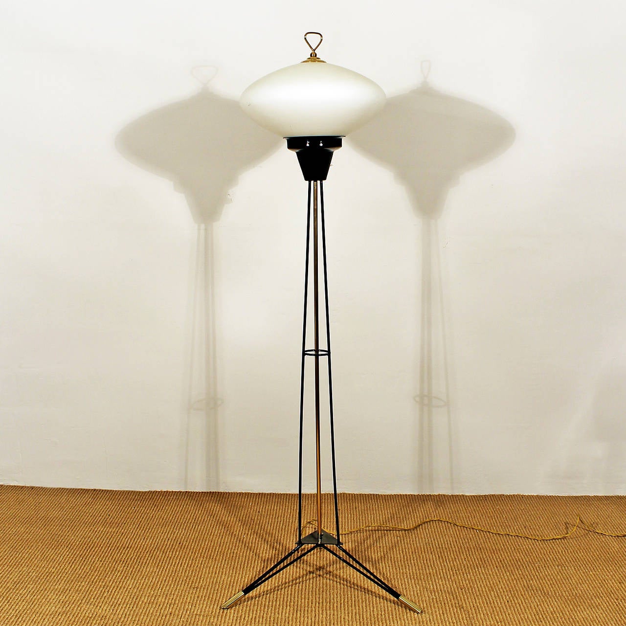 Tripod standing lamp, black lacquered metal, brass and white opaline.
Italy, circa 1960.

Measures: lampshade diameter 33 cm.