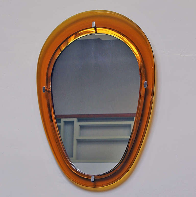 Mirror with an orange glass frame (minor losses), holded back by chrome plated hooks, original mirror.
Italy c. 1960