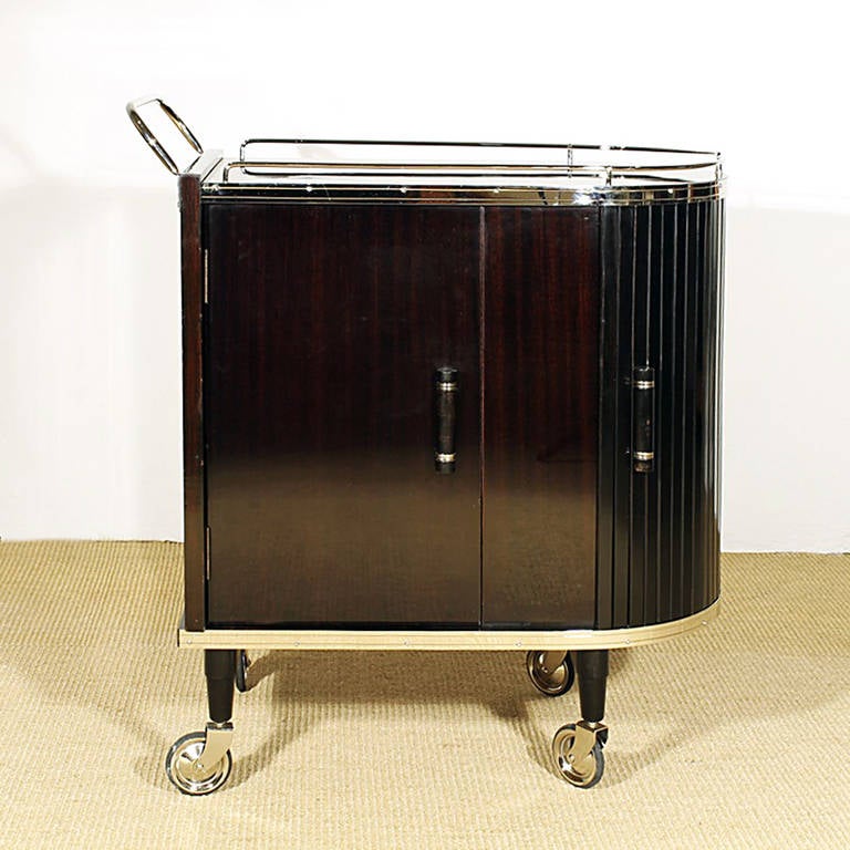 Roller dry bar cart, stained french polished mahogany veneer, one regular door and one roll door, ash wood interiors with drawer and shelves, nickel plated hardware.
France circa 1950