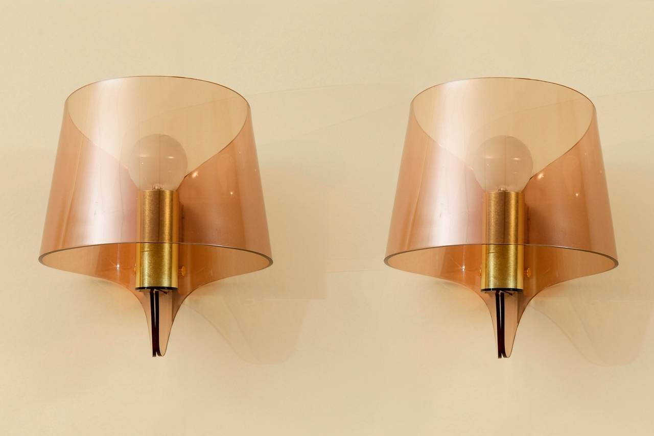 A pair of wall sconces in brass and smoked plexiglass.