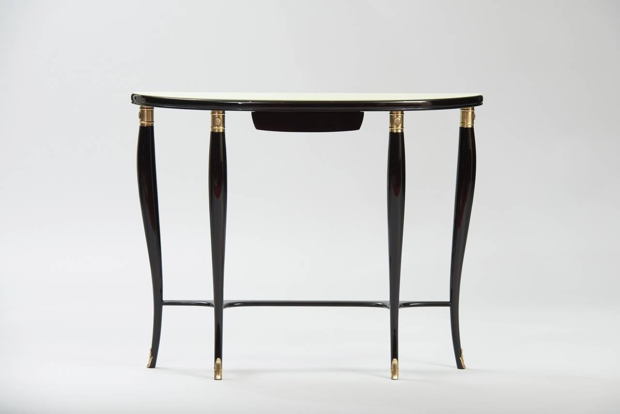 Ebonized wood, brass and white glass top demilune console.