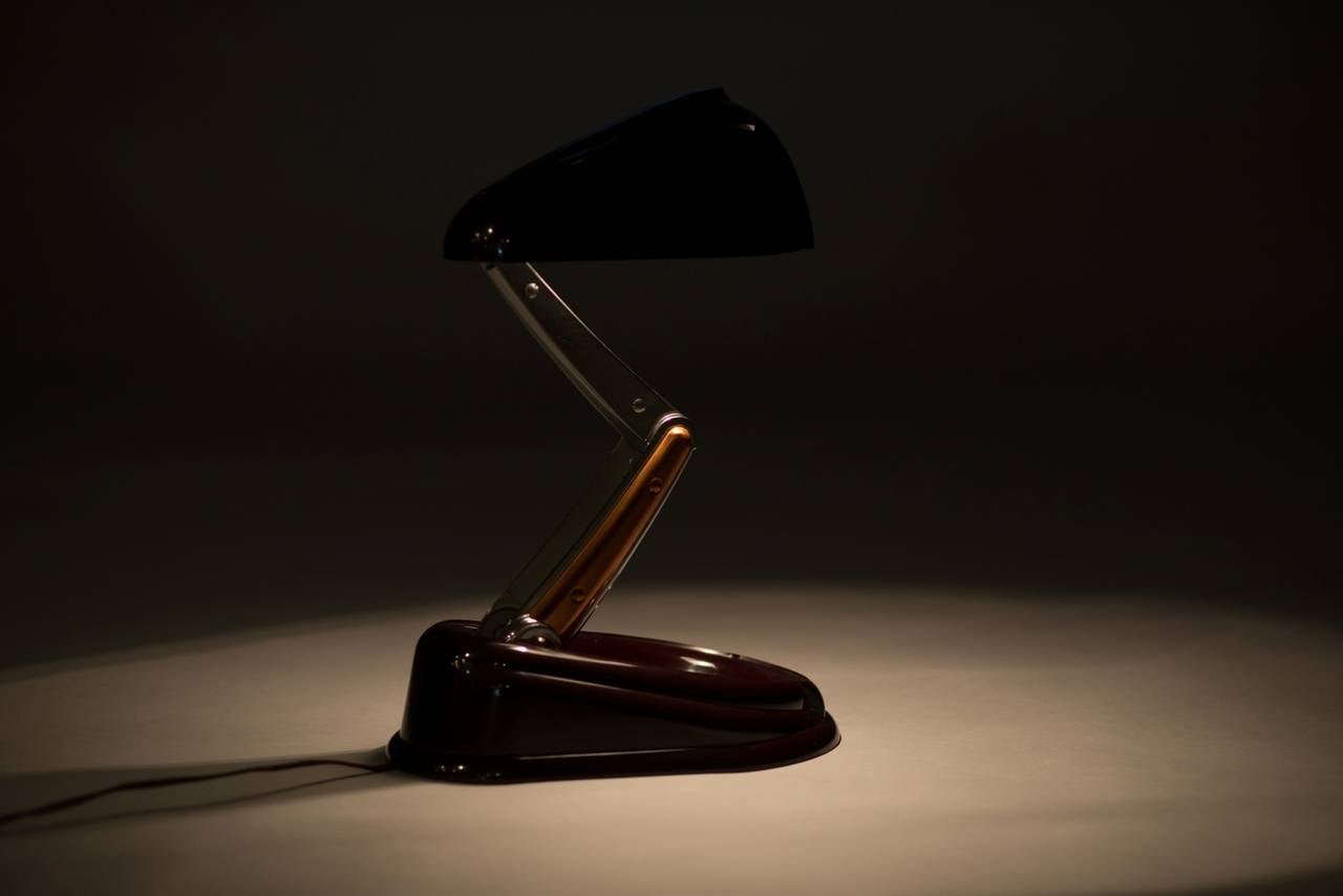 Brown bakelite, chrome and cooper folding desk table lamp, “Bolide” model.
Producer: La Société Jumo, Paris.
Closed measures: D 0.28 m, W 18 m, H 14 m – D 11.02 in, W 7.08 in, H 5.51 in.
Open measures: H 0.44 m – 17.32 in.