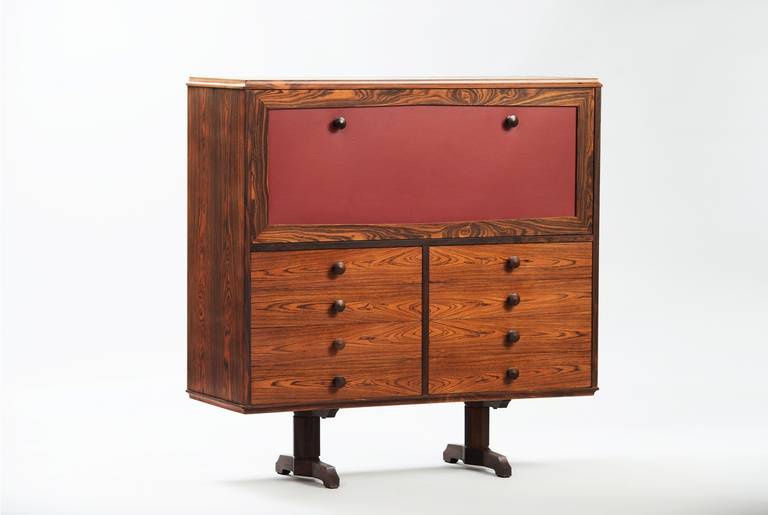 Rosewood and red skai cabinet with drop-front door and drawers.